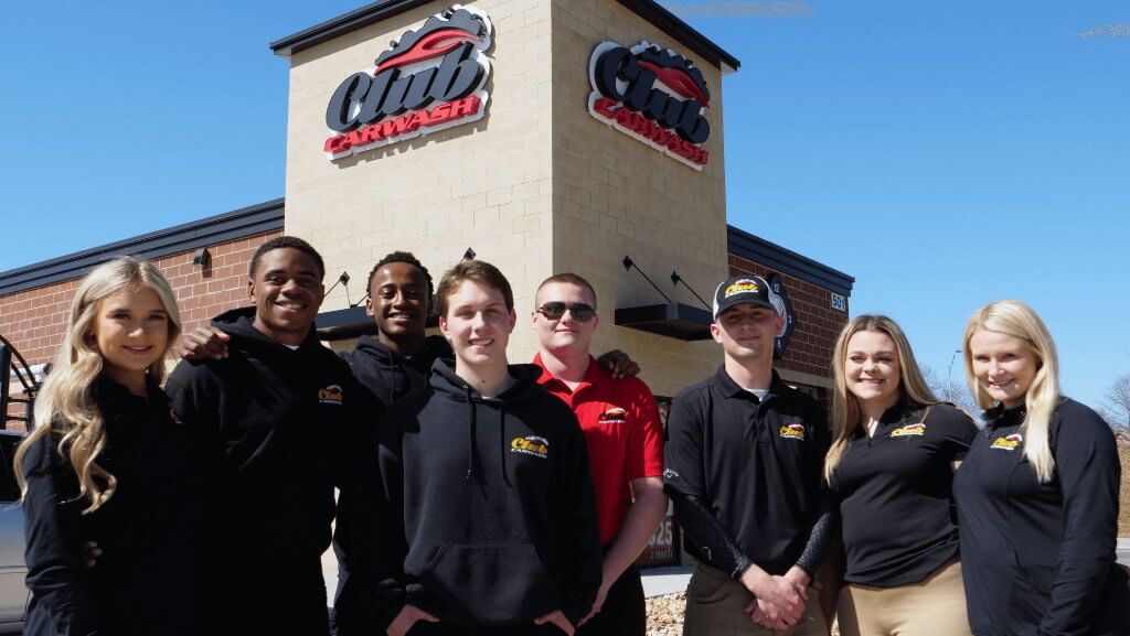 group of employees gathered in front of the car wash smiling