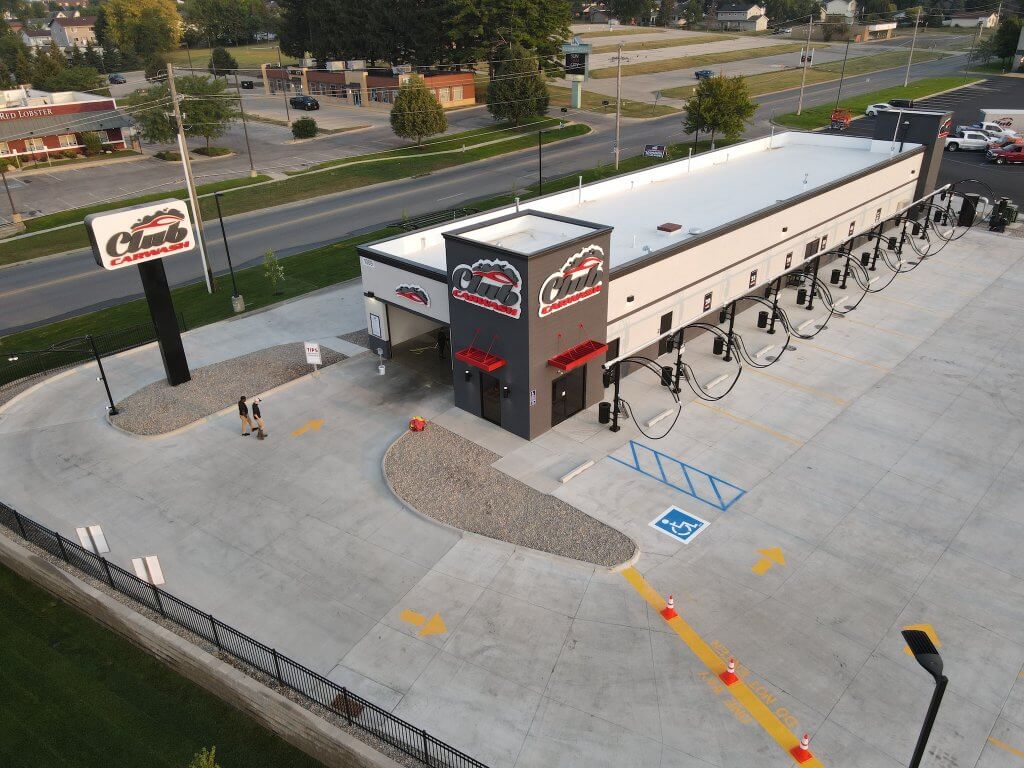 Bird eye view of club car wash, large tall tower with club car wash logo, parking lot to the right