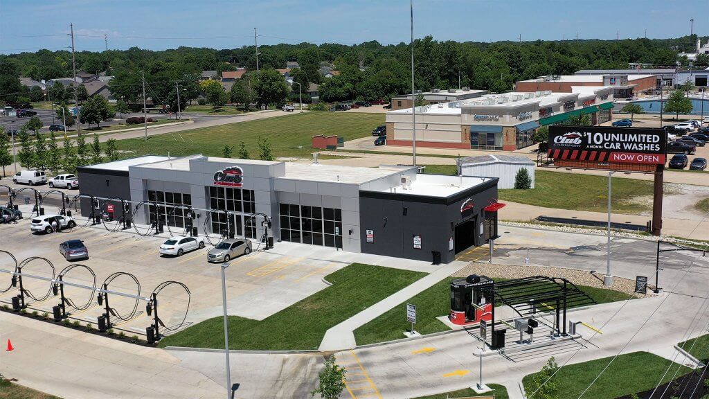 renovated car dealership with black windows in the front and green grass surrounding with a billboard on right side
