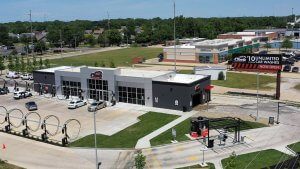 renovated car dealership with black windows in the front and green grass surrounding with a billboard on right side