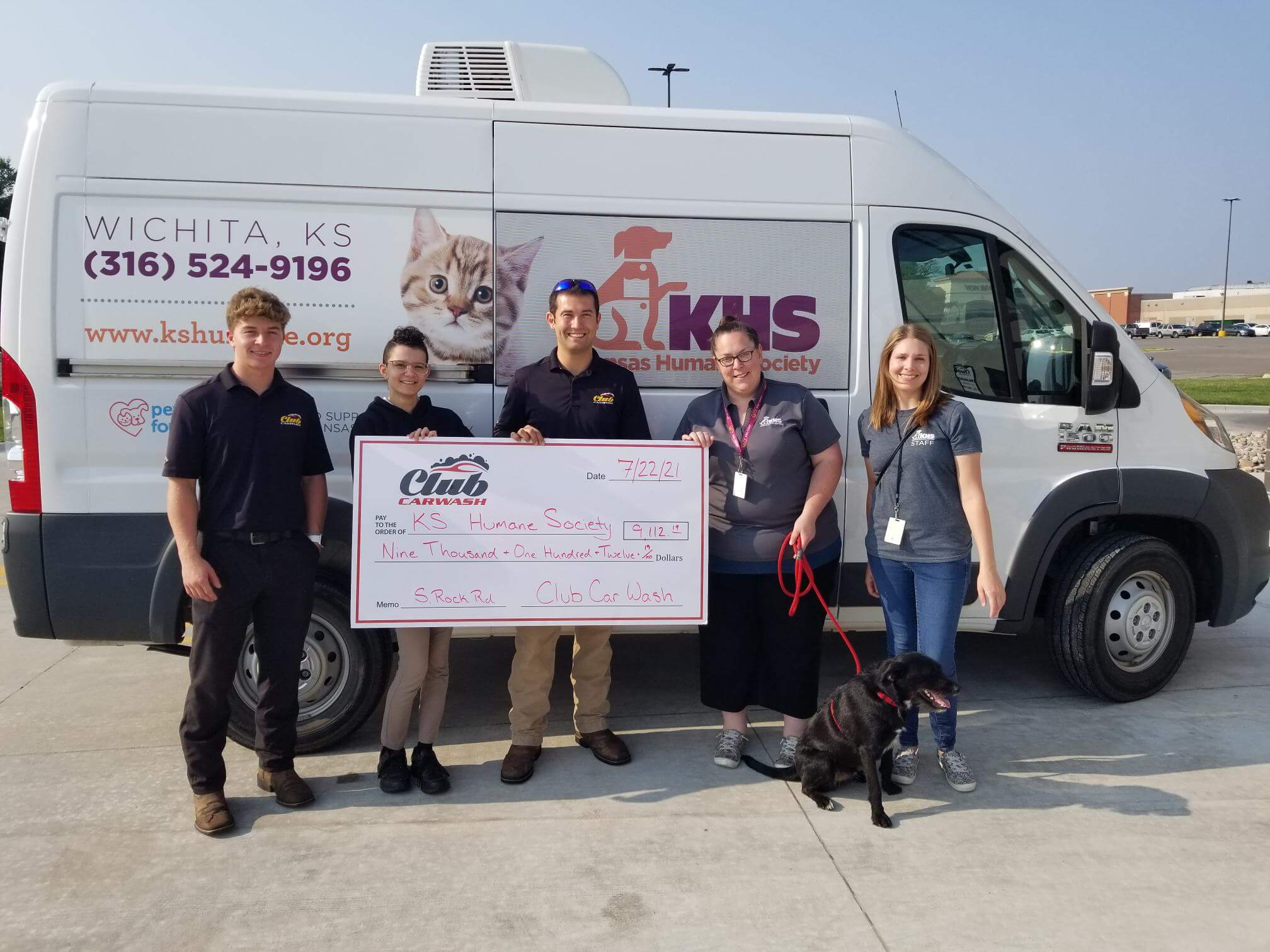 group of club car wash employees with kansas humane society representatives and dog with a check
