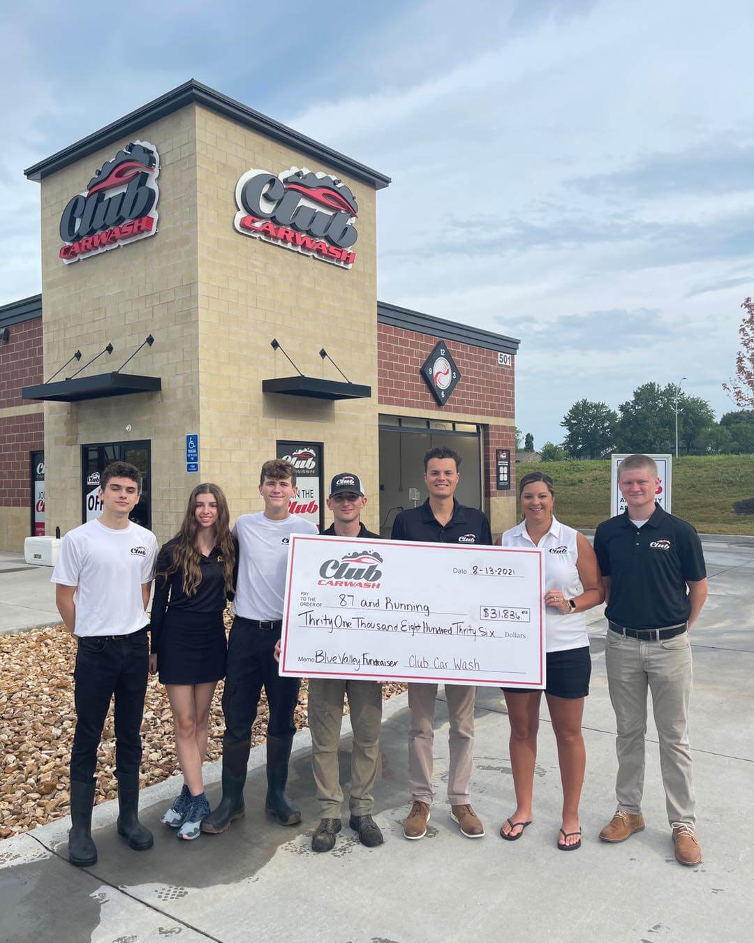 Check presentation with Club Car Wash employees holding check in front of a location.