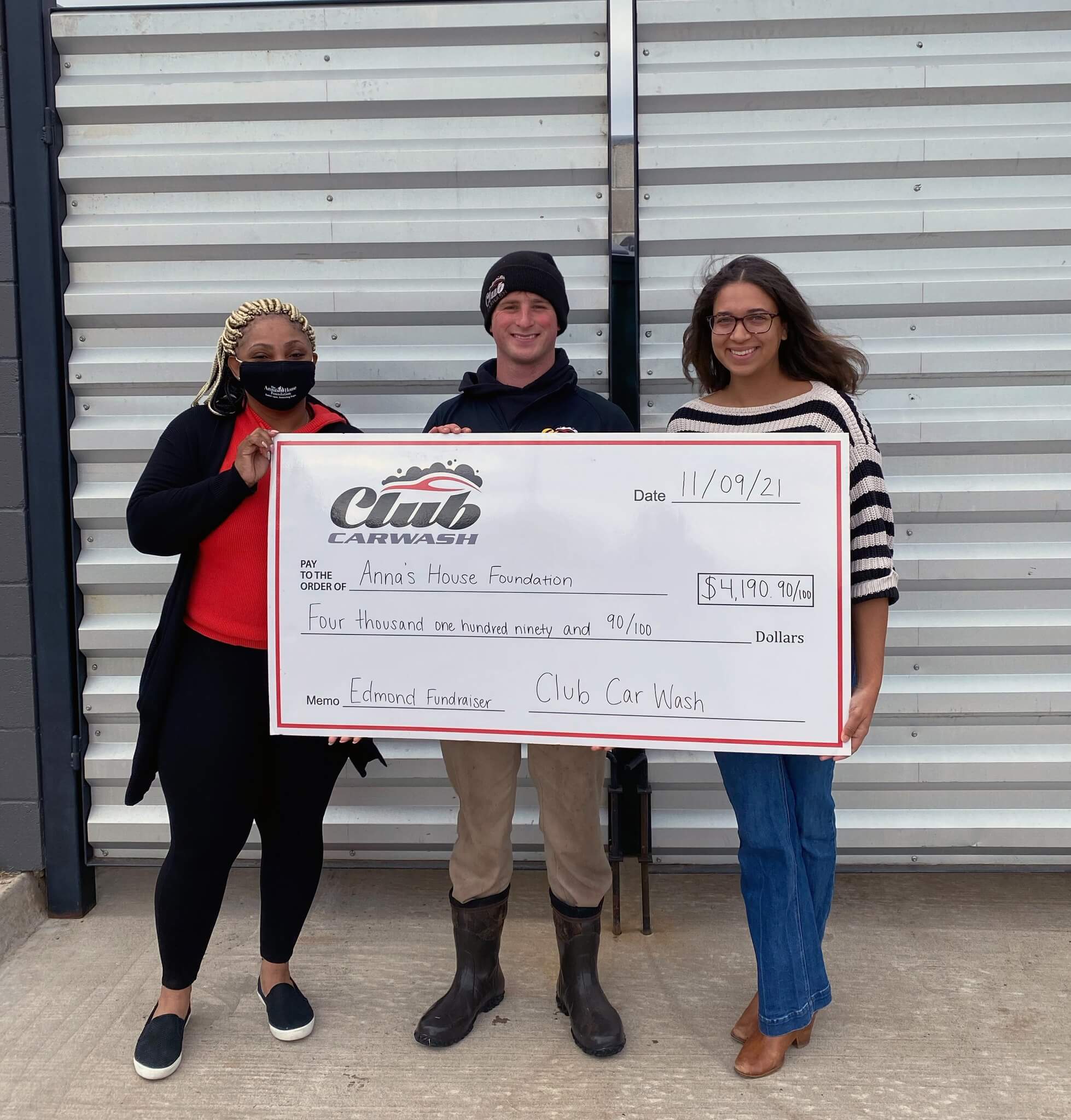 Anna's House Foundation representatives holding a large check with Club Car Wash employee.