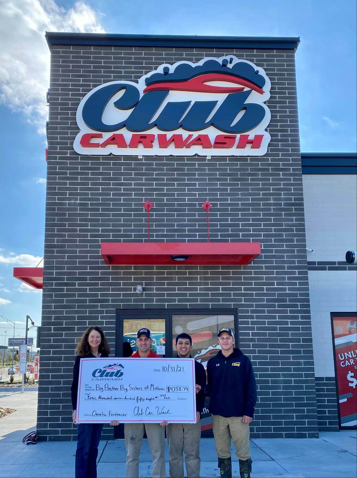 Club Car Wash employees and representatives from Big Brothers Big Sisters of Midland present check in front of Club Car Wash location.